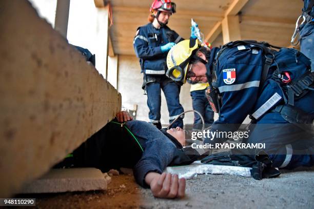 French rescuer helps a victim as he takes part in a simulation of an earthquake in Bouira, northern Algeria, on April 17, 2018. - An imaginary...