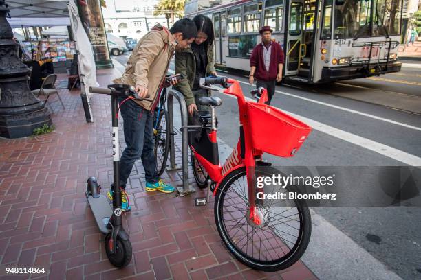 People unlock an Uber Technologies Inc. Jump Bike, right, while standing with a Bird Rides Inc. Shared electric scooter in San Francisco, California,...