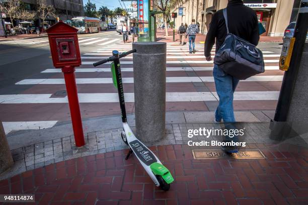 Pedestrian walks past a Neutron Holdings Inc. LimeBike shared electric scooter on Market Street in San Francisco, California, U.S., on Friday, April...