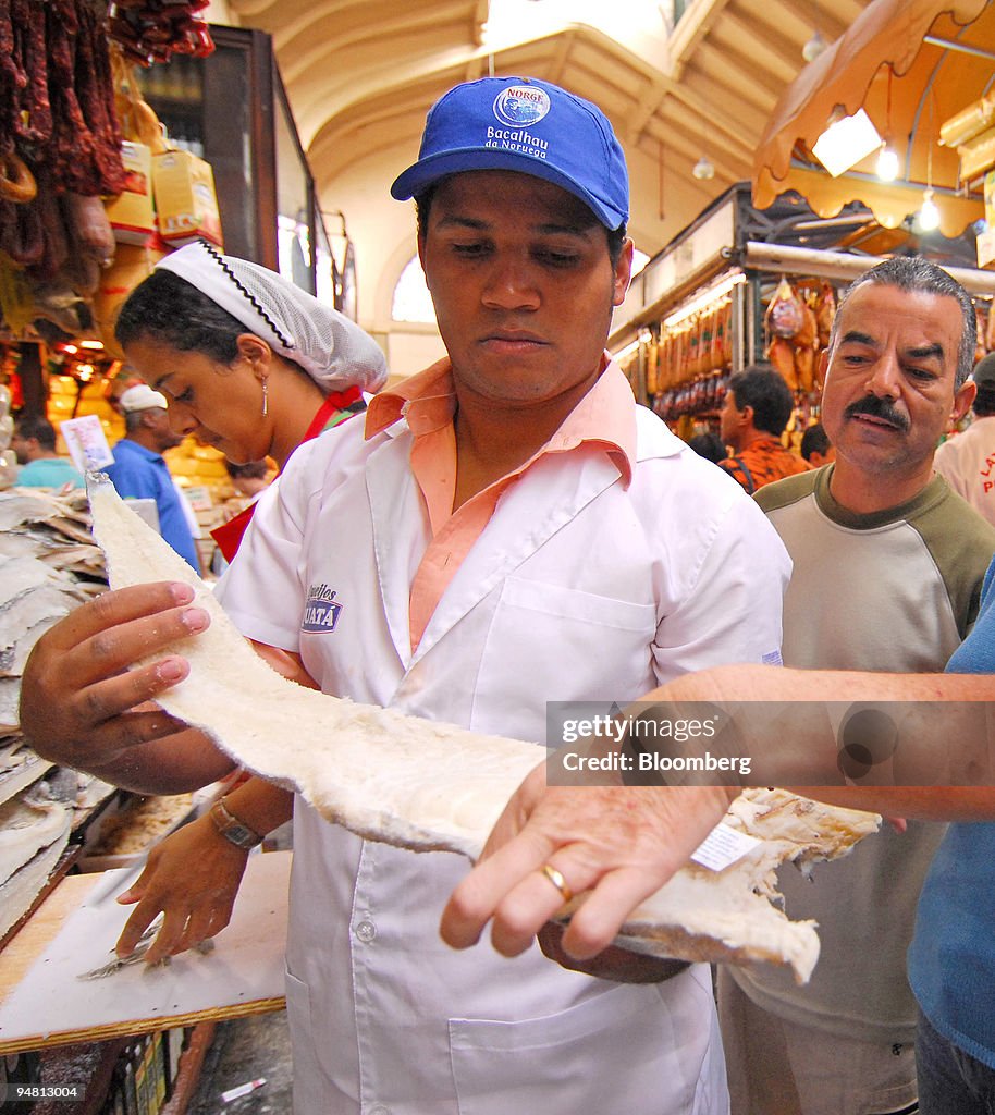 A salesman holds a piece of bacalhau, or salted, dried codfi
