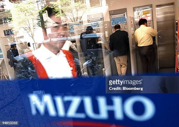 Man walks out of a Mizuho bank branch while people use ATM machines in central Tokyo Thursday, April 21, 2005.