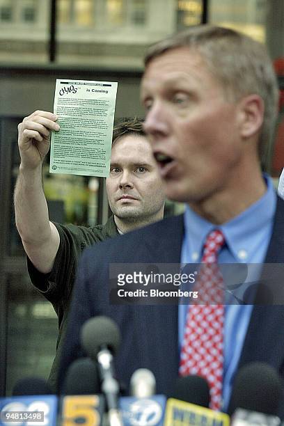 An unidentified United Airlines flight attendant holds a pamphlet citing potential union action while United Airlines CFO Jake Brace addresses the...