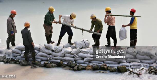 Workers place sandbags across the Hei Tao Ba river in an attempt to contain water turned white by a nearby gas leak in Gao Qiao village, Kai Xian...