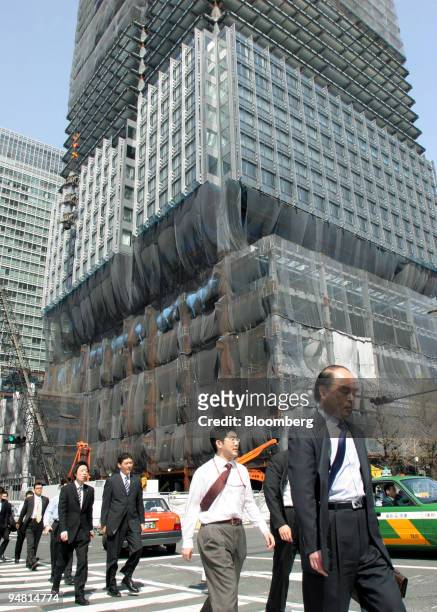 Pedestrians walk past in front of Shin Marunouchi building under construction in Tokyo, Japan, Tuesday, April 4, 2006. Tokyo may be closing the gap...