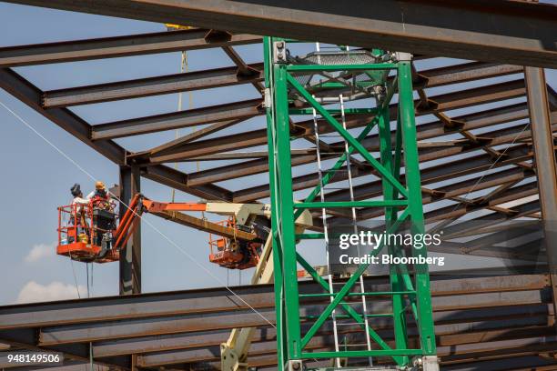 Workers stand on a JLG Industries Inc. Boom lift while building the foundation of the control tower under construction at the New International...