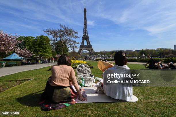Asian tourists picnic in the Gardens of Trocadero below the Eiffel Tower on a warm weather Spring day on April 18, 2018 in Paris.