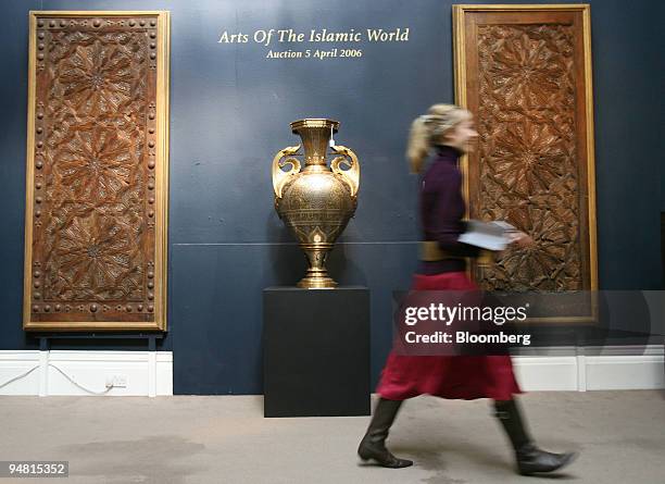 Sotheby's employee walks past a Spanish gold and silver damascened forged iron vase from 1881 and a pair of 17th-19th century spanish wooden doors at...