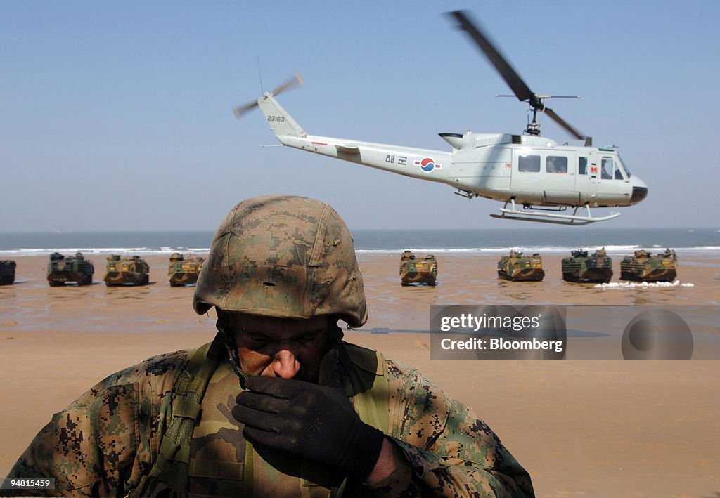 U.S. marine covers his face from sand as a helicopter comes