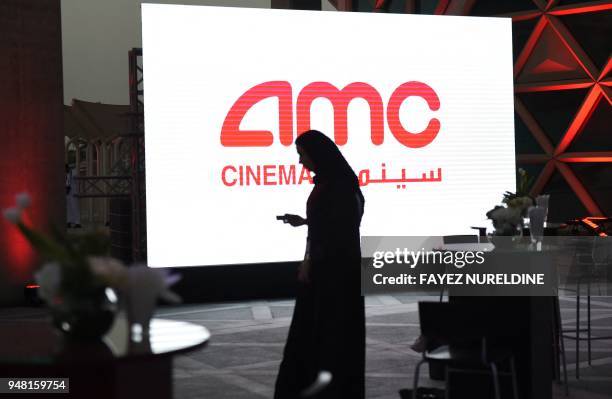 Saudi man holds his cellphone during a cinema test screening in Riyadh on April 18, 2018. - Blockbuster action flick "Black Panther" play at a cinema...