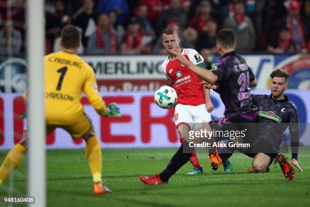 Daniel Brosinski of Mainz passes the ball past Marc-Oliver Kempf and goalkeeper Alexander Schwolow of Freiburg before referee Guido Winkmann calls a...
