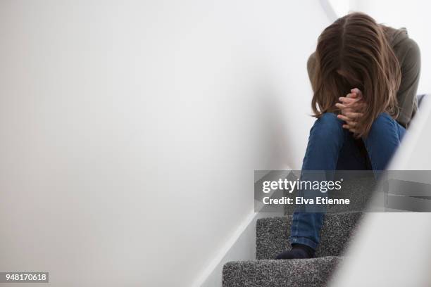 teenage girl sitting on stairs with head down in despair - mental health depression foto e immagini stock