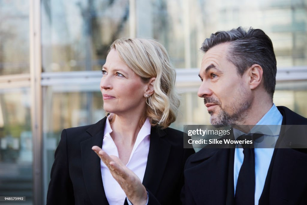 Portrait of a businesswoman and businessman standing in front of modern building talking