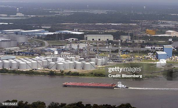 Barges pass by storage tanks at oil refineries along the Houston Ship Channel in Houston, Texas, Wednesday, June 9, 2004. Crude oil futures fell to...