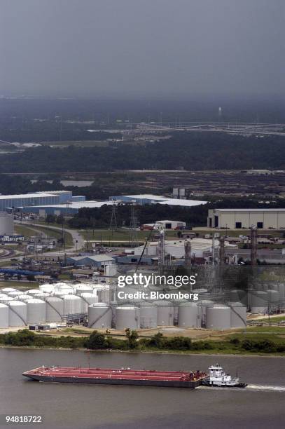 Barges pass by storage tanks at oil refineries along the Houston Ship Channel in Houston, Texas, Wednesday, June 9, 2004. Crude oil futures fell to...