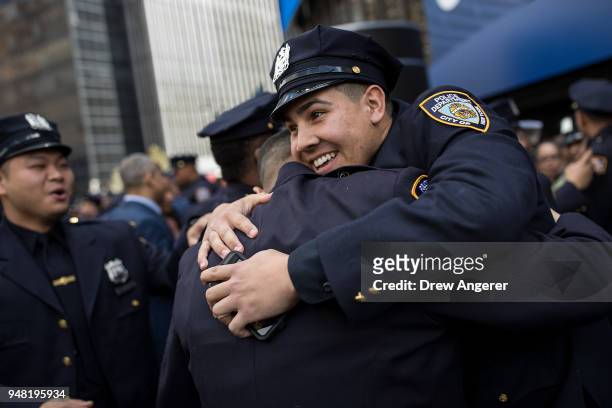 New members of the New York City Police Department embrace at the conclusion of their police academy graduation ceremony at the Theater at Madison...