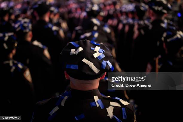 The newest members of the New York City Police Department stand at attention after confetti fell at the conclusion of their police academy graduation...