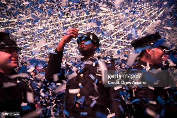 The newest members of the New York City Police Department celebrate as confetti falls at the conclusion of their police academy graduation ceremony...