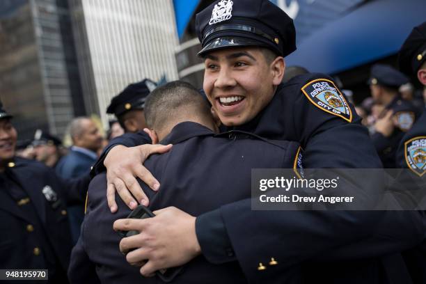 New members of the New York City Police Department embrace at the conclusion of their police academy graduation ceremony at the Theater at Madison...