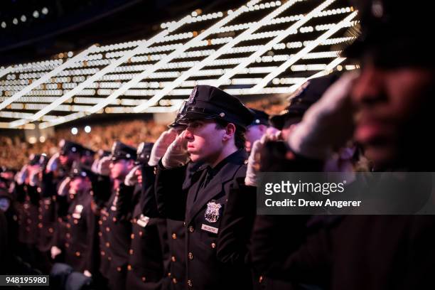 The newest members of the New York City Police Department salute during their police academy graduation ceremony at the Theater at Madison Square...