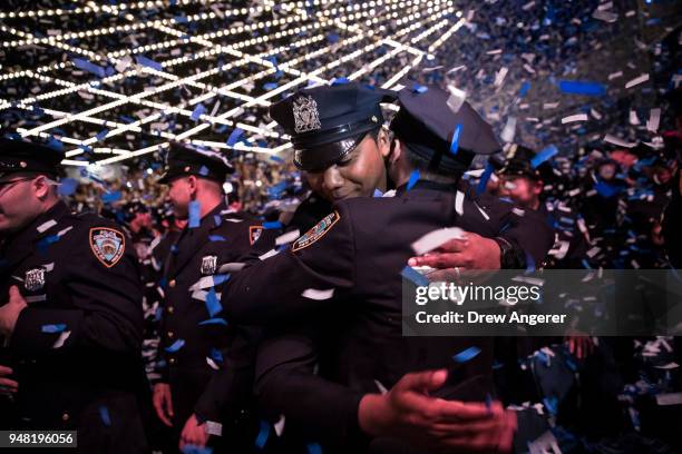 New members of the New York City Police Department embrace as confetti falls at the conclusion of their police academy graduation ceremony at the...