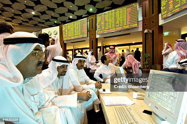 Men look over a quote screen on the floor of the Dubai Financial Market, in the Dubai World Trade Centre in Dubai, United Arab Emirates Sunday,...