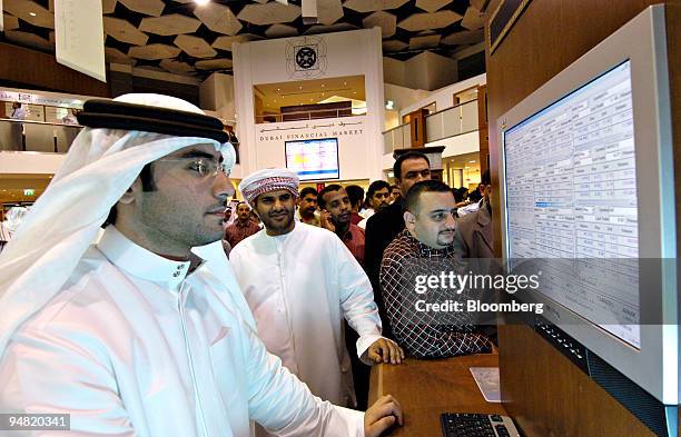 Men look over a quote screen on the floor of the Dubai Financial Market, in the Dubai World Trade Centre in Dubai, United Arab Emirates Sunday,...