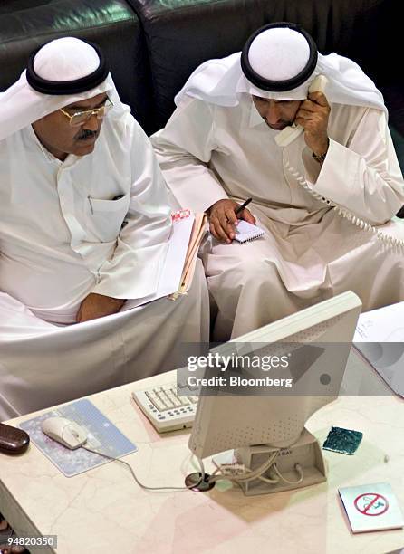 Men look over a quote screen on the floor of the Dubai Financial Market, in the Dubai World Trade Centre in Dubai, United Arab Emirates Sunday,...