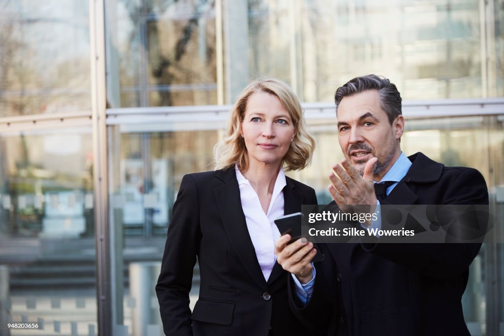 Portrait of a businesswoman and businessman standing in front of modern building talking