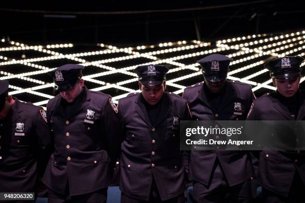 The newest members of the New York City Police Department bow their heads during the benediction at their police academy graduation ceremony at the...