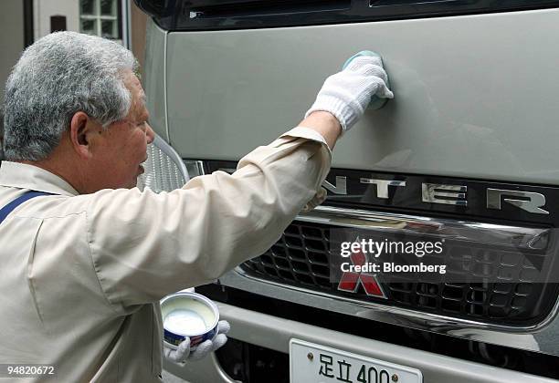 Man waxes his Mitsubishi Fuso Canter truck in Tokyo Tuesday, March 29, 2005. Mitsubishi Fuso Truck & Bus Corp., DaimlerChrysler AG's Japanese...