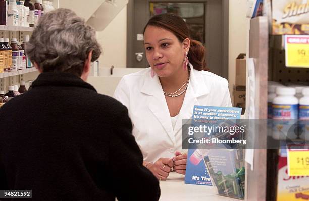Pharmacy Technician Jessica Camacho helps a customer at a Walgreen's Pharmacy in New York on June 1, 2004. Drugmakers are competing to offer the...