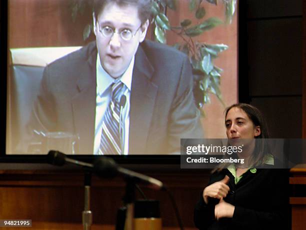 Translator signs while Federal Communications Commission Chairman Kevin J. Martin is shown on a video monitor during an FCC meeting on March 17, 2006...