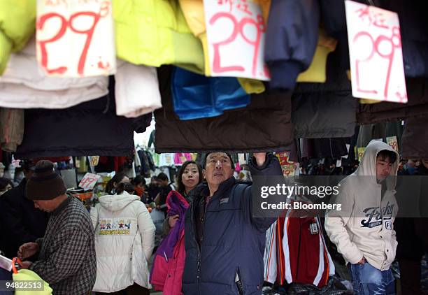 Man looks at coats for sale in a shop in Beijing, China, on January 11, 2006. China's consumer prices rose in February at the slowest pace in five...