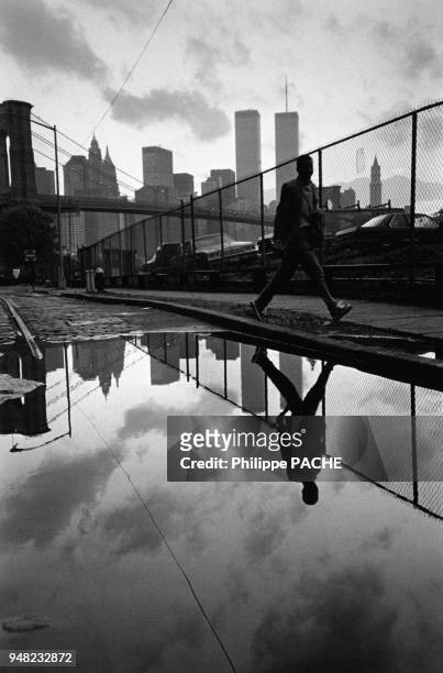 Passant reflété dans une flaque d'eau à New York, en 1998, Etats-Unis.