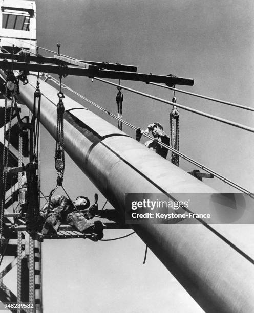 Deux ouvriers, en équilibre, repeignent le George Washington Bridge à New York City, Etats-Unis en 1946.