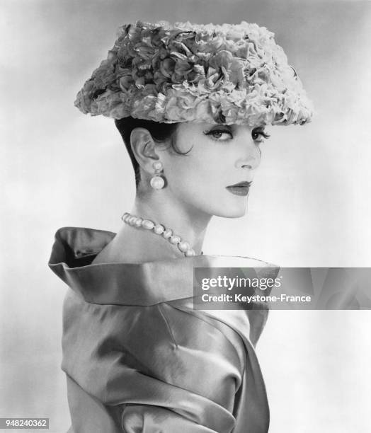 Mannequin présentant les modèles Mr John de la Collection Printemps/Eté 1956: le chapeau 'Coquette' en pétales de roses roses, porté avec un manteau...