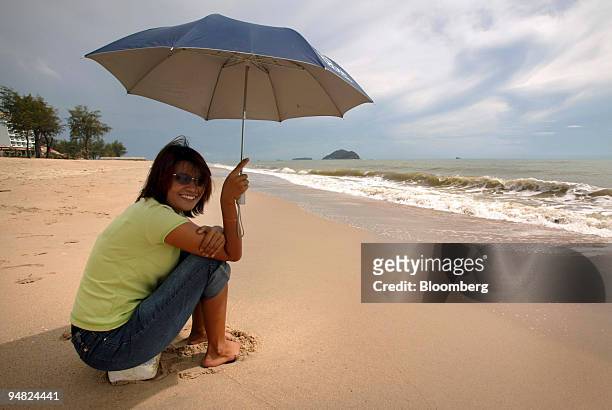 Smiling Thai woman sits on a deserted beach in Hat Yai in southern Thailand May 1, 2004. Recent clashes with muslim extremists in the region has...