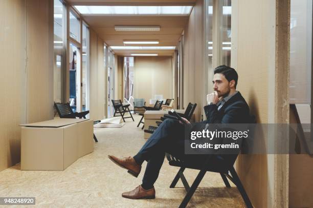 pensive young businessman sitting in the office - narrow stock pictures, royalty-free photos & images