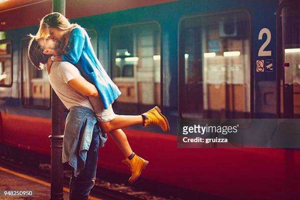 passionate young man and woman kissing beside the train at the railway station - amor à primeira vista imagens e fotografias de stock