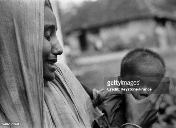 Une femme qui vient de perdre deux membres de sa famille attend pour pouvoir bénéficier de l'aide alimentaire, circa 1950, à Falta, Inde.