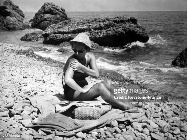 Une femme bronze sur les galets de la plage en août 1956 à Paraggi, Italie.