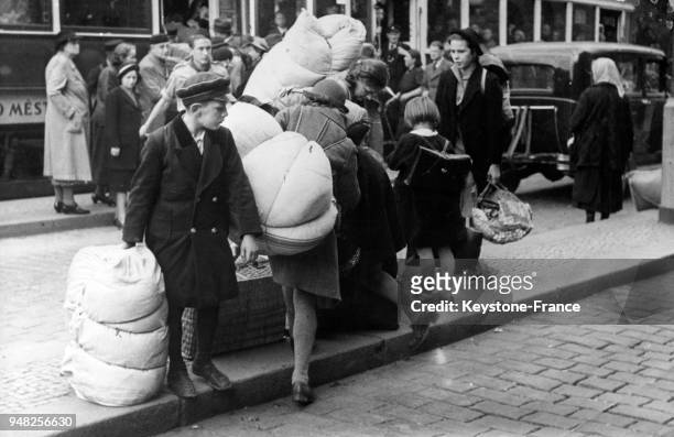 Porteurs de gros sacs de linge et de literie, les réfugiés du territoire des Sudètes affluent à Prague, Tchécoslovaquie en octobre 1938.