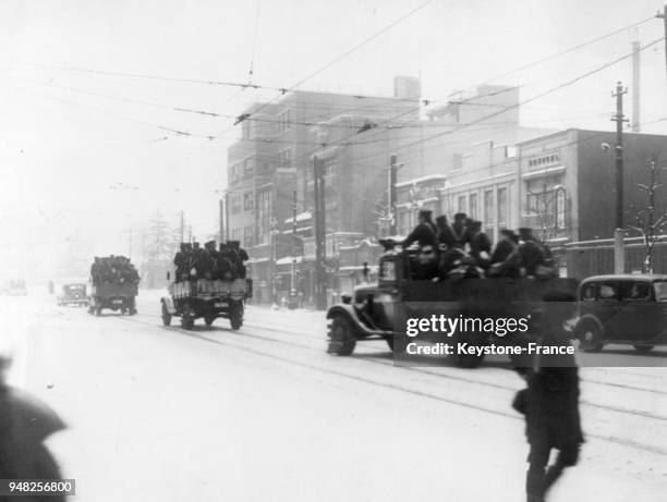 Les Corps des Marines traversent la ville dans des camions pour se positionner devant les immeubles gouvernementaux, à Tokyo, Japon en 1936.