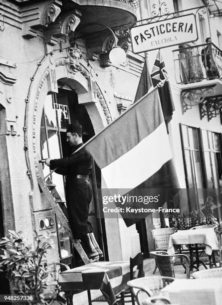 Un milicien fasciste installe un drapeau français à la devanture d'un café à Stresa, Italie en avril 1935.