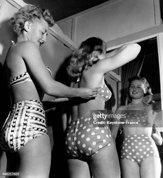 Ruth Gesch, Miss Auto Club 1948, et Sara Hirsch, Miss Muscle Beach 1948, essayant des maillots de bain deux pièces, dont l'un à pois, dans une...