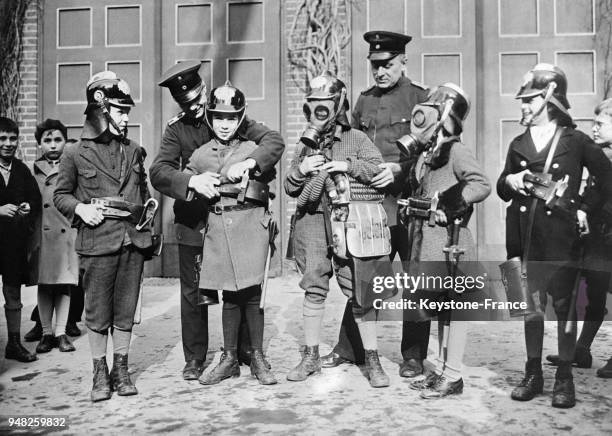 Dans une caserne de pompiers, les écoliers sont familiarisés avec l'habillement des pompiers, à Berlin, Allemagne en 1932.