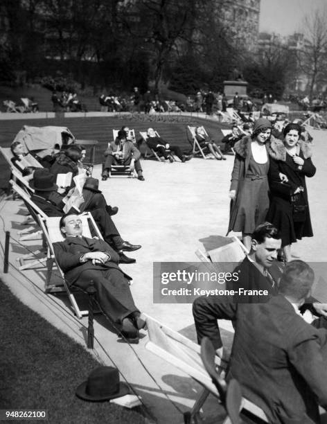 Des travailleurs bronzent au soleil sur les bancs de l'Embankment Gardens pendant la pause-déjeuner le 10 avril 1931 à Londres, Royaume-Uni.