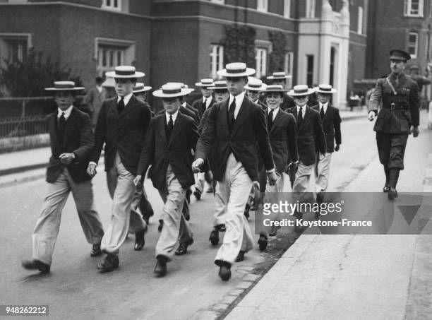 Des étudiants portant l'uniforme du prestigieux établissement scolaire Harrow se rendent à une parade escorté par un militaire, le 1er octobre 1930 à...