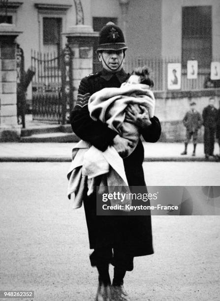 Un policier tient dans ses bras un bébé enveloppé dans une couverture pour l'emmèner à l'hôpital après avoir été sauvé d'un incendie, à Londres,...