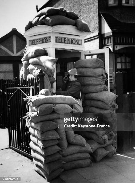 Une femme en uniforme téléphone d'une cabine protégée par des sacs de sable, à Londres, Royaume-Uni le 7 septembre 1939.